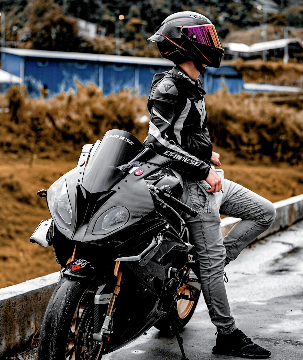 Hombre con chaqueta de cuero negro montando motocicleta negra durante el día