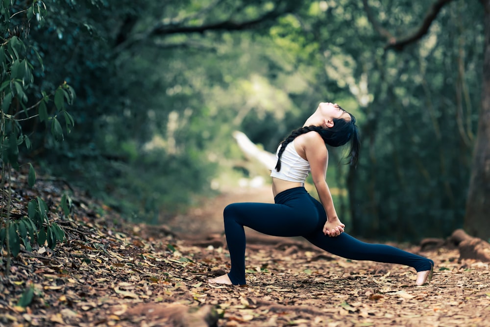 woman in white shirt and black leggings sitting on brown dirt road during daytime