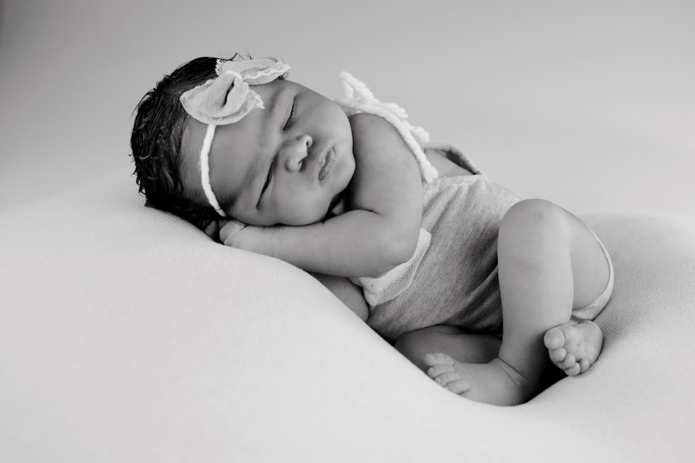 grayscale photo of baby lying on bed