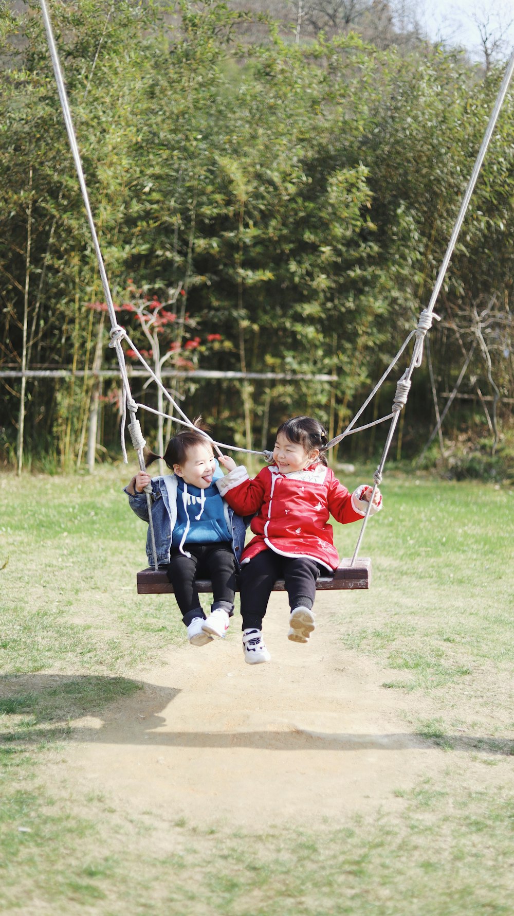 2 boys sitting on swing during daytime