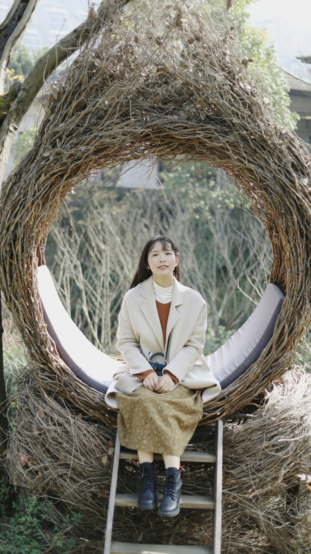 woman in white blazer and brown skirt sitting on brown round nest