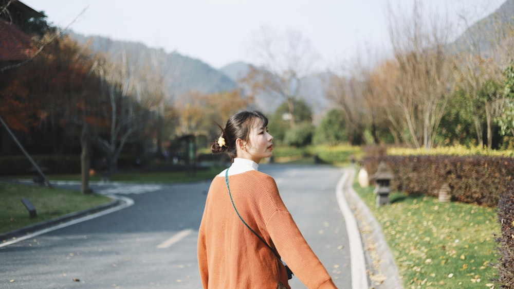 woman in orange dress standing on road during daytime