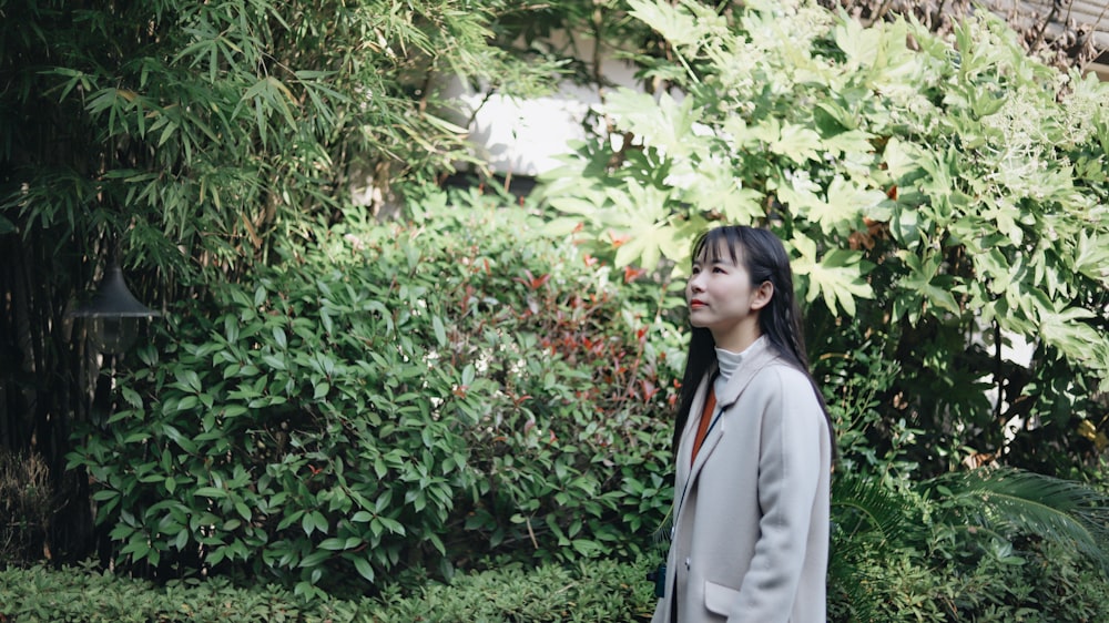 woman in gray blazer standing near green plants during daytime