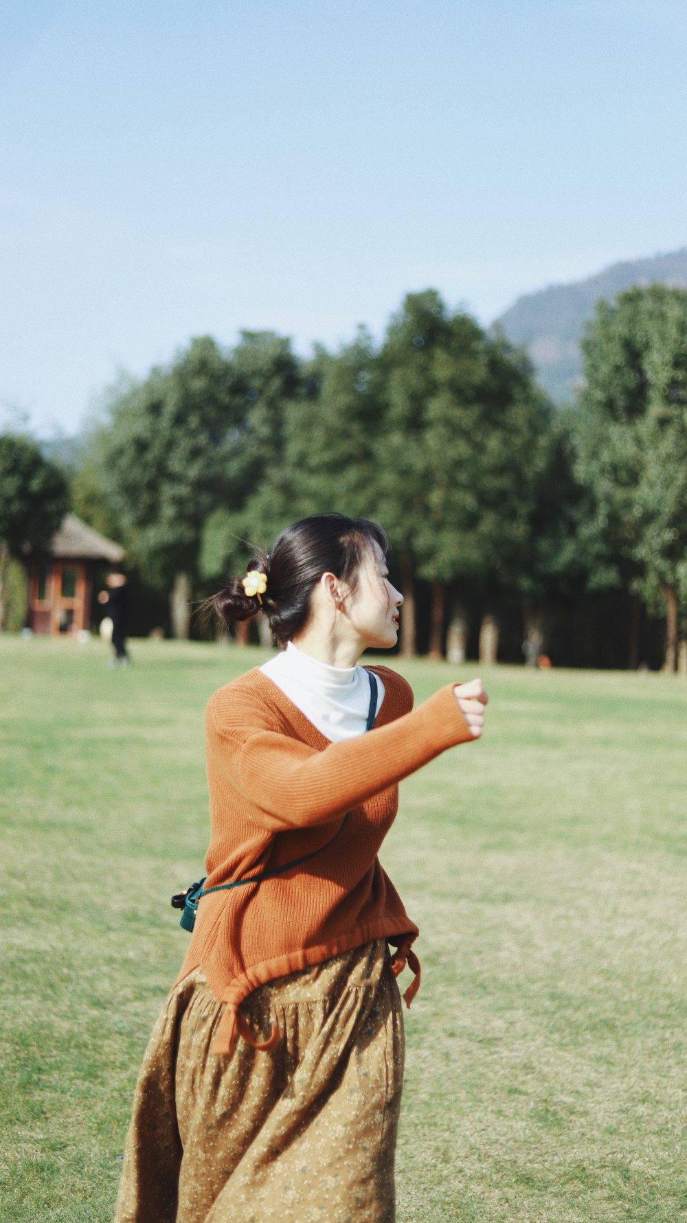 woman in orange long sleeve shirt standing on green grass field during daytime