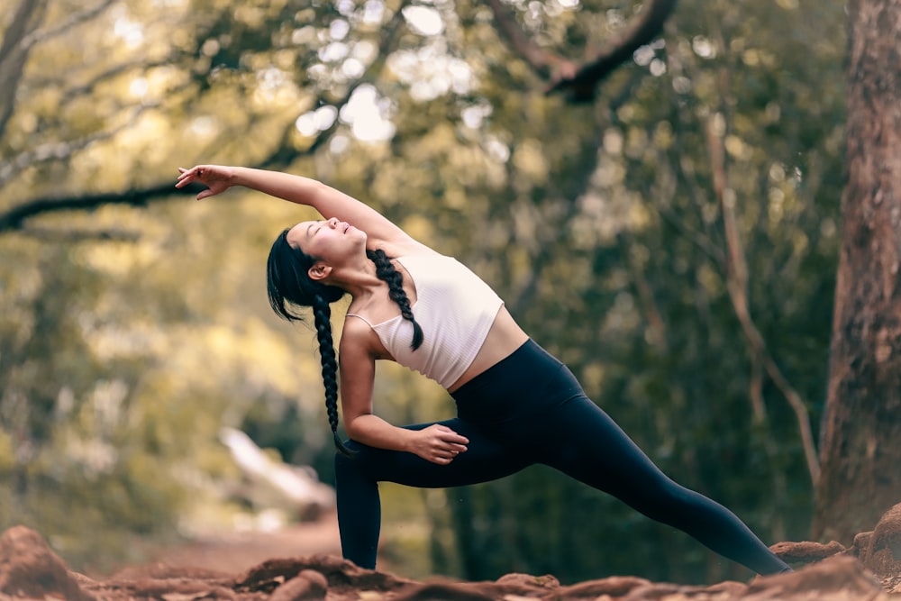 Frau in weißem Tanktop und schwarzen Leggings beim Yoga tagsüber