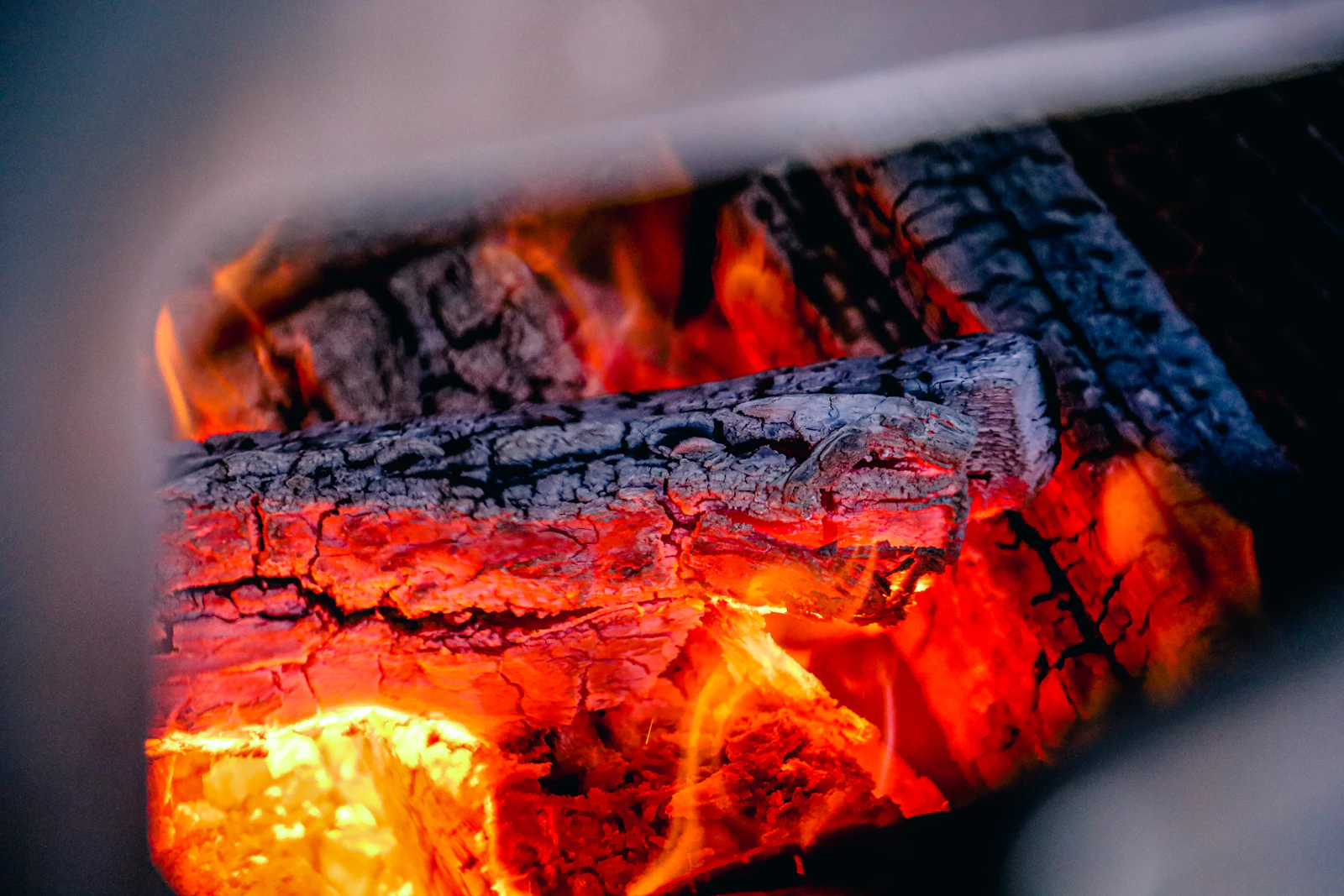 Glowing wood and flames inside a barbecue smoker firebox