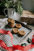 A baker’s hands gently placing freshly baked cookies into a kraft paper box tied with twine.