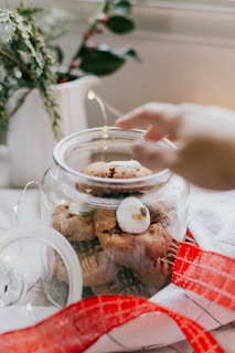 A hand reaching for a freshly baked peanut butter cookie from a jar