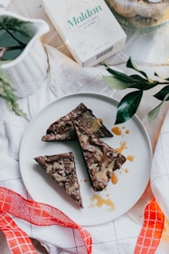 Artfully plated chocolate brownie with a drizzle of caramel sauce on a warm beige ceramic plate.