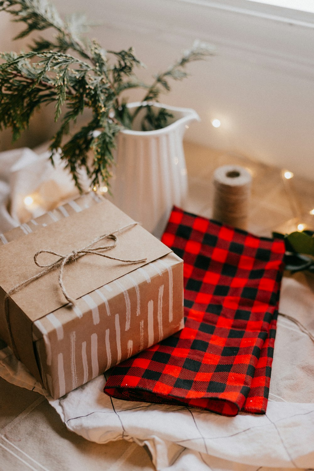 Caja de regalo marrón y blanco sobre tela de cuadros rojos y blancos