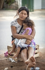 woman in white and blue floral dress sitting on brown wooden bench