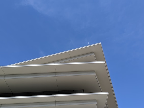 Architects reviewing blueprints on a modern building site under clear skies.