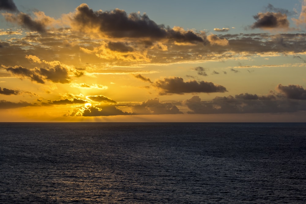 body of water under cloudy sky during sunset