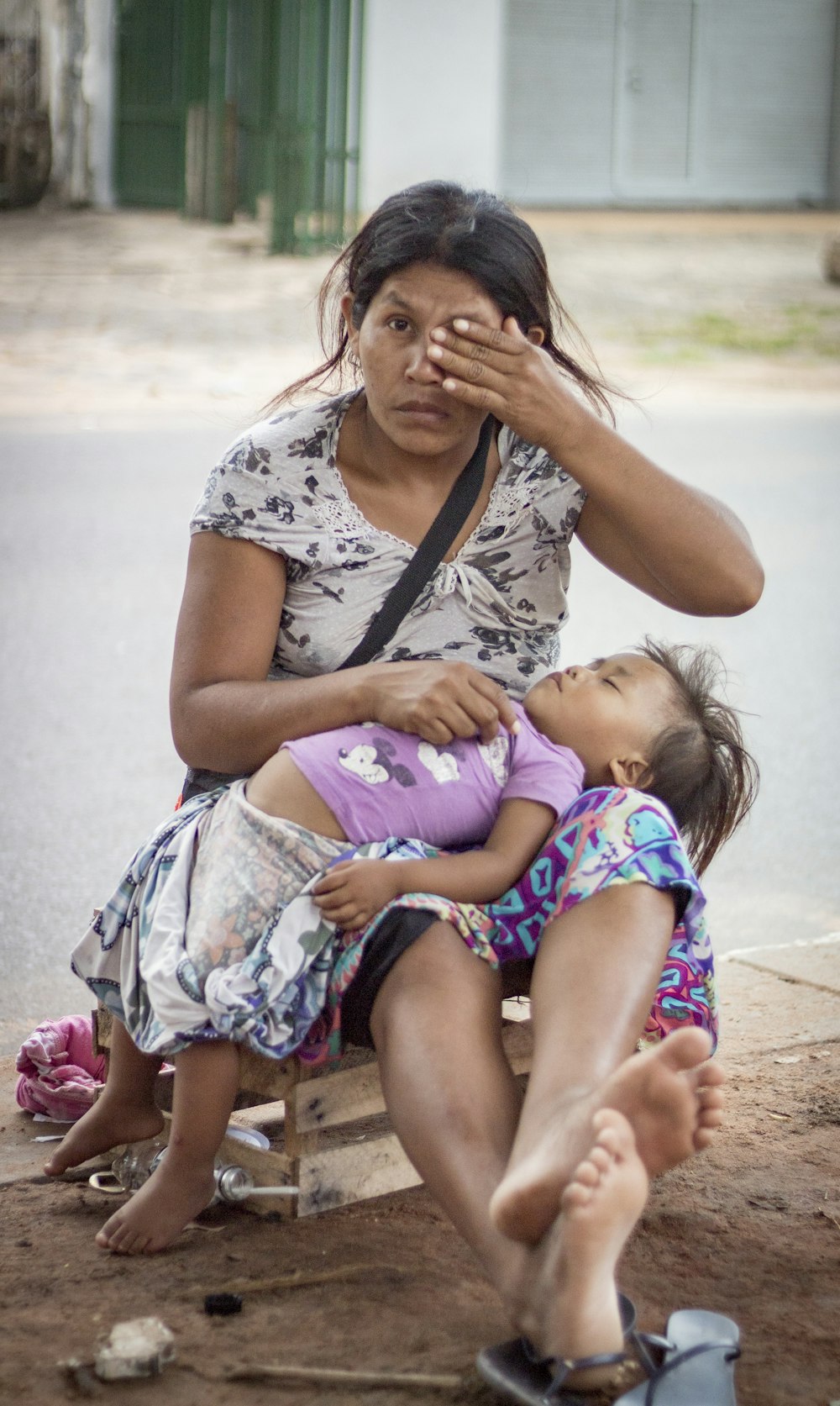 Mujer en camisa floral blanca y negra que lleva a la niña en vestido rosa