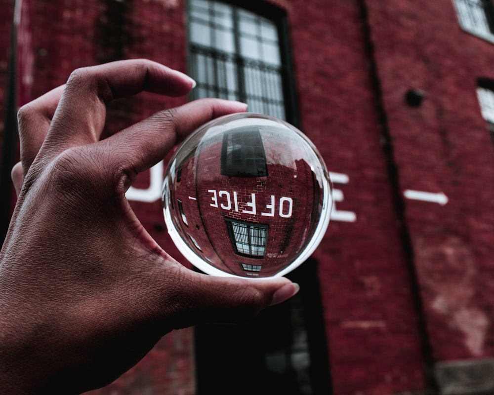 person holding round clear glass container