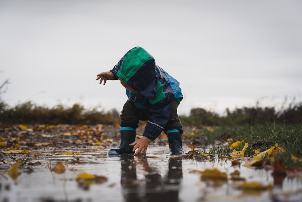 Persona in giacca verde e pantaloni neri in piedi sull'acqua durante il giorno