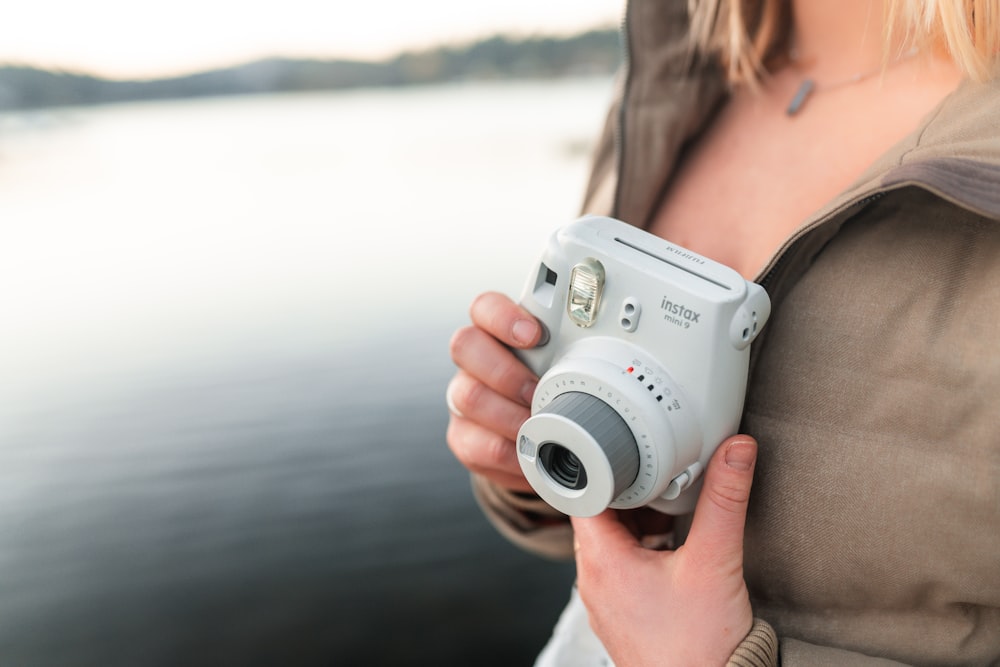 Mujer sosteniendo una cámara blanca y gris