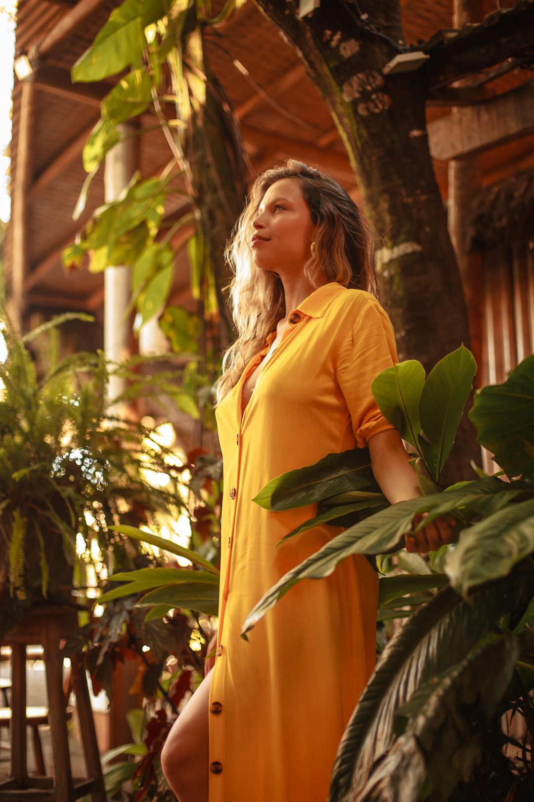 woman in yellow long sleeve shirt standing near green leaf plant during daytime