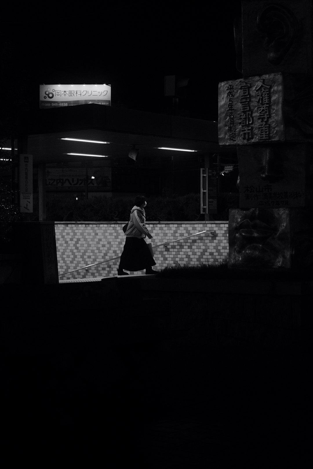 woman in black and white dress standing near white and black concrete building during nighttime