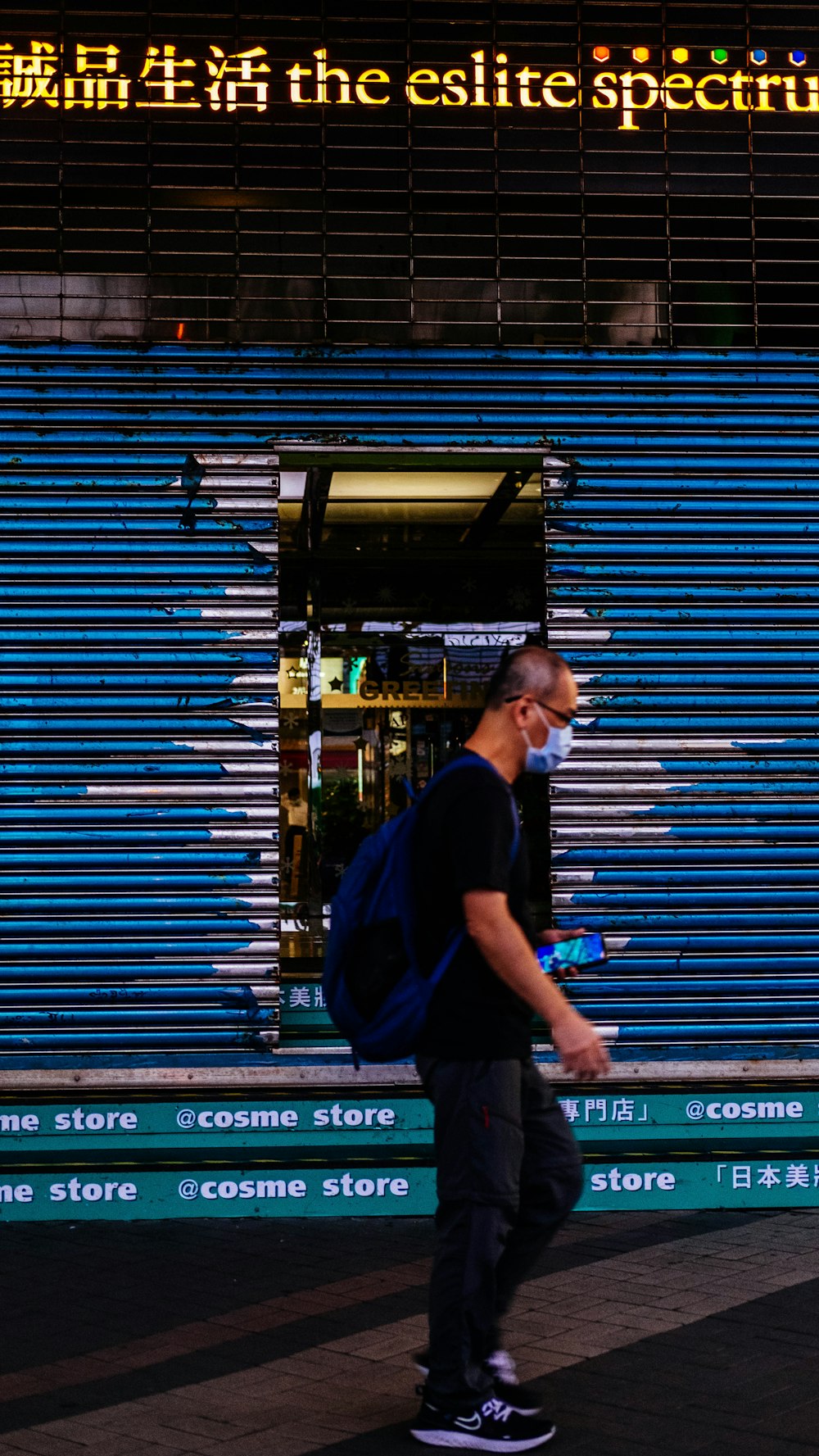 Hombre con camiseta azul de cuello redondo de pie frente a la puerta enrollable azul
