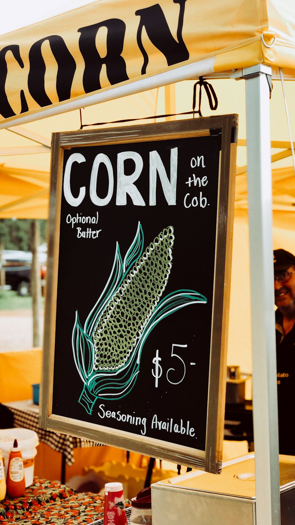 a sign advertising corn on the cob at a farmer's market