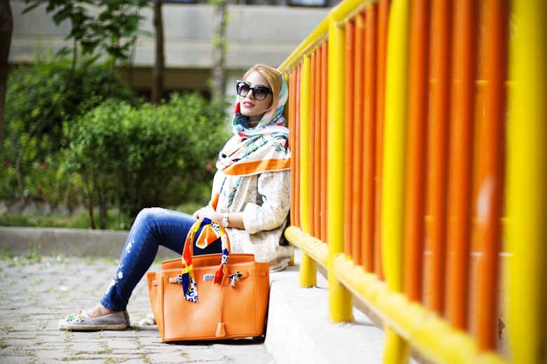 woman in blue denim jeans sitting on orange bench during daytime