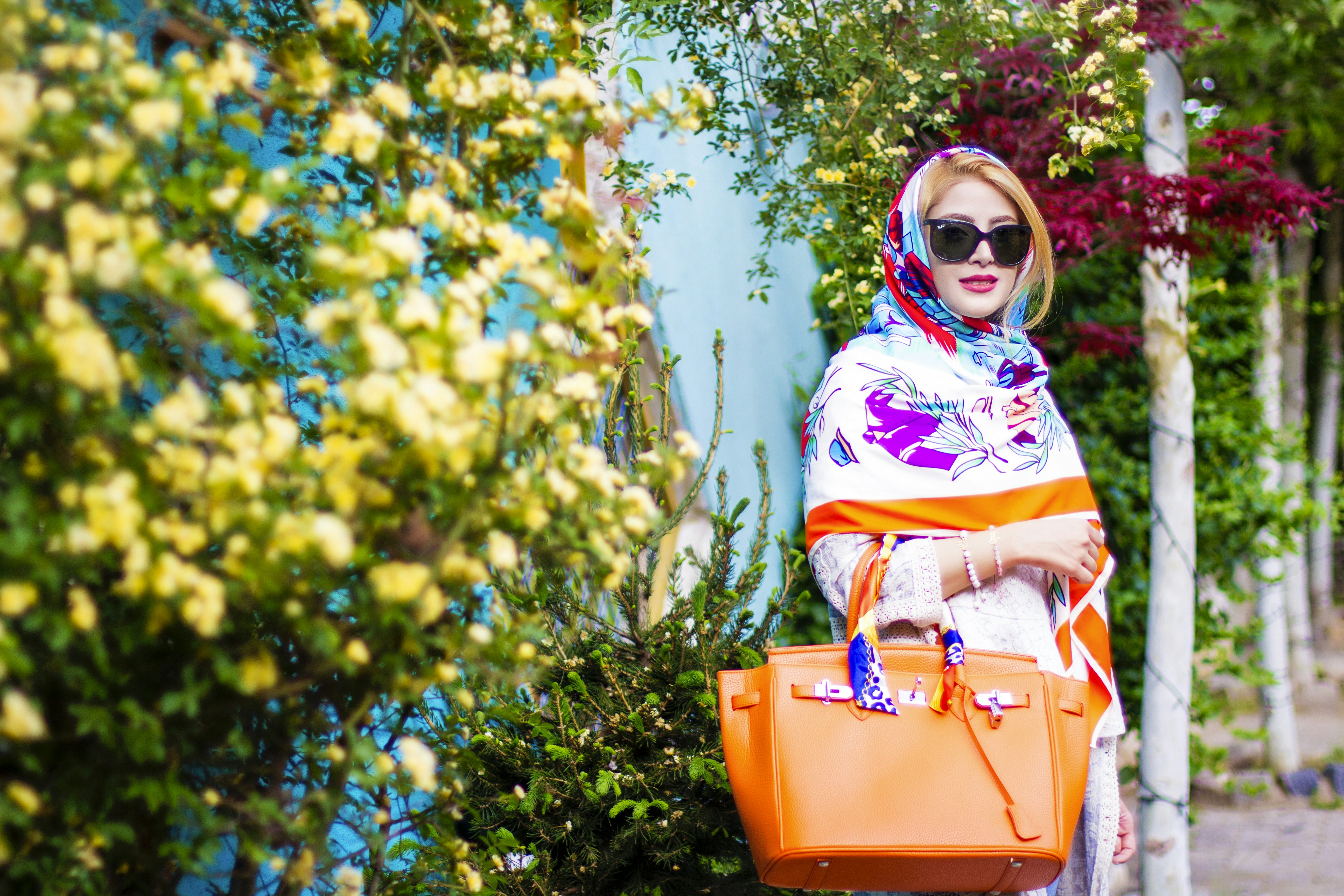 woman in yellow and pink hijab standing beside yellow flowers during daytime