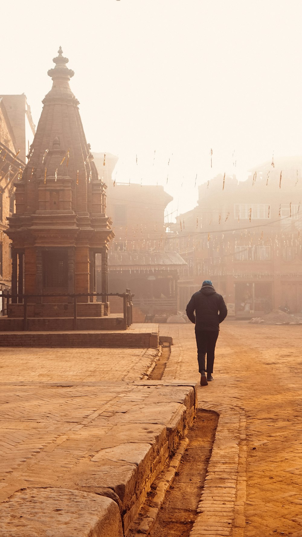 man in black jacket walking on sidewalk during daytime