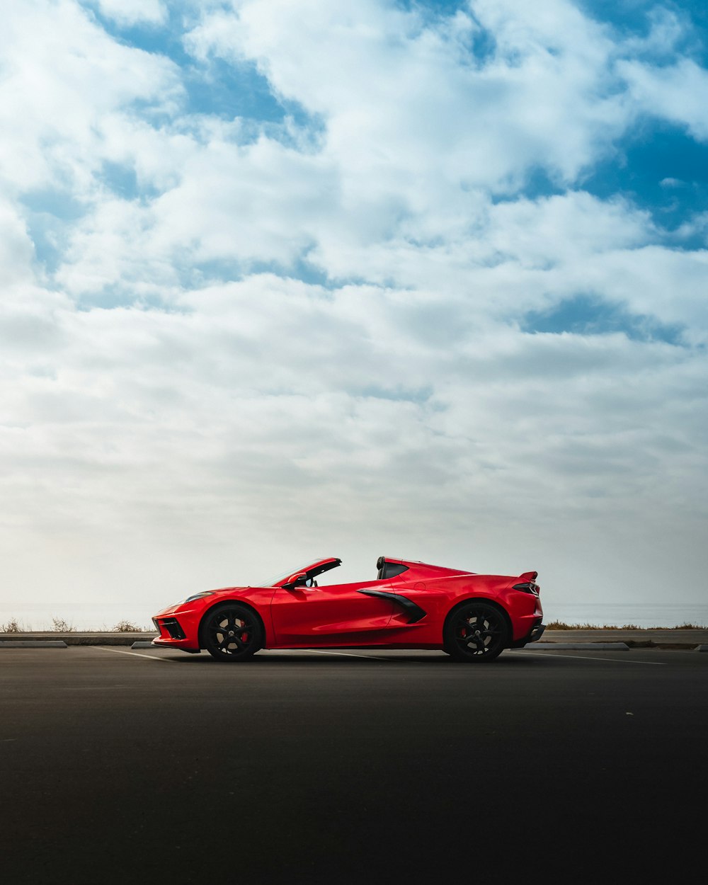 Roter Ferrari 458 Italia tagsüber auf braunem Sand unter weißen Wolken