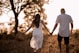 man and woman holding hands while walking on grass field during daytime