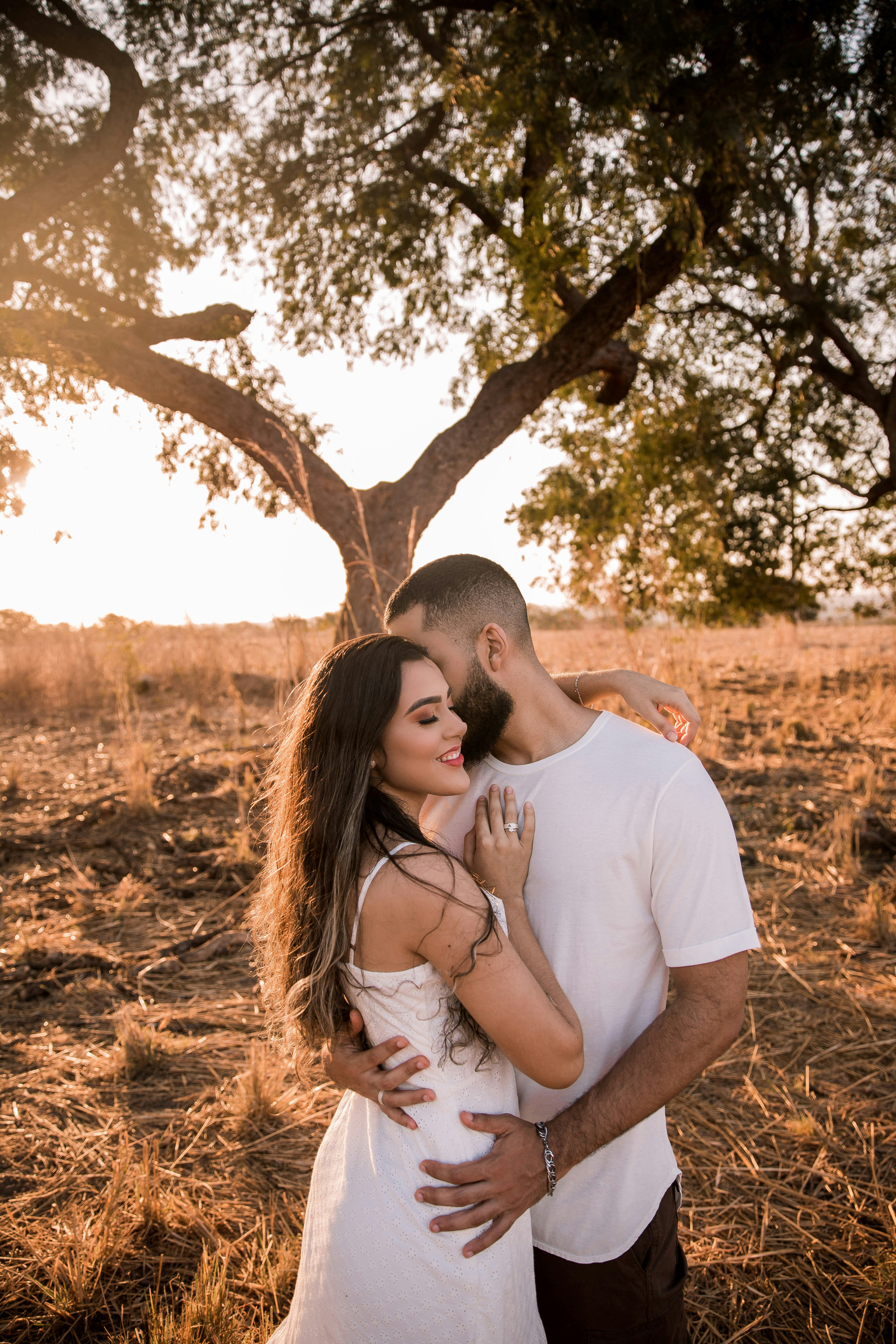 man and woman kissing under tree during daytime