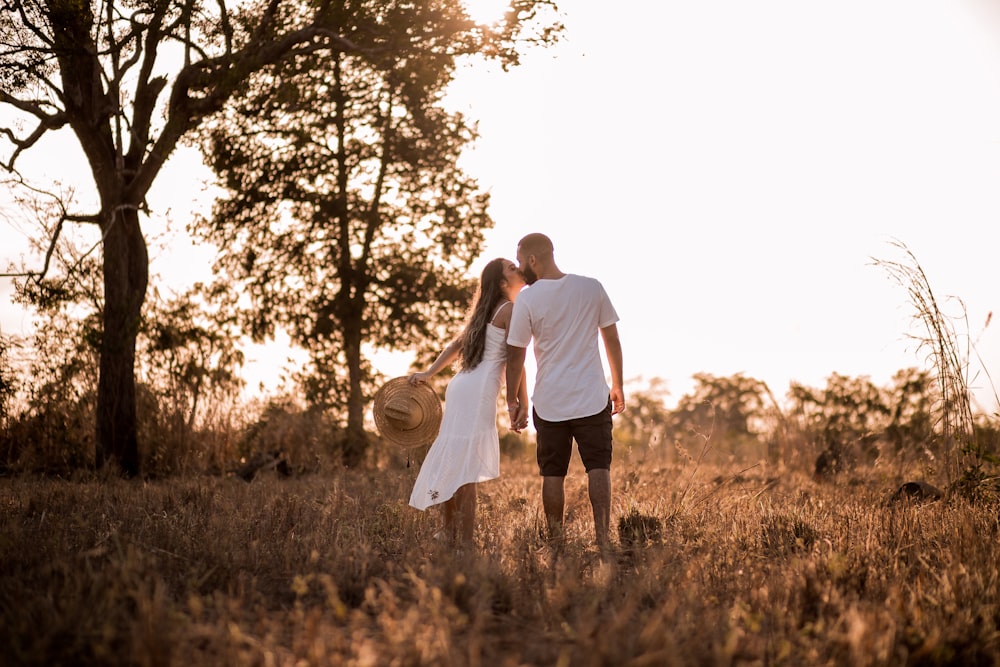 man and woman holding hands while walking on grass field during daytime