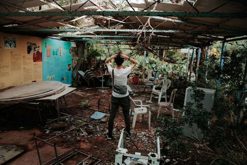 man in white t-shirt and black pants standing on brown wooden floor