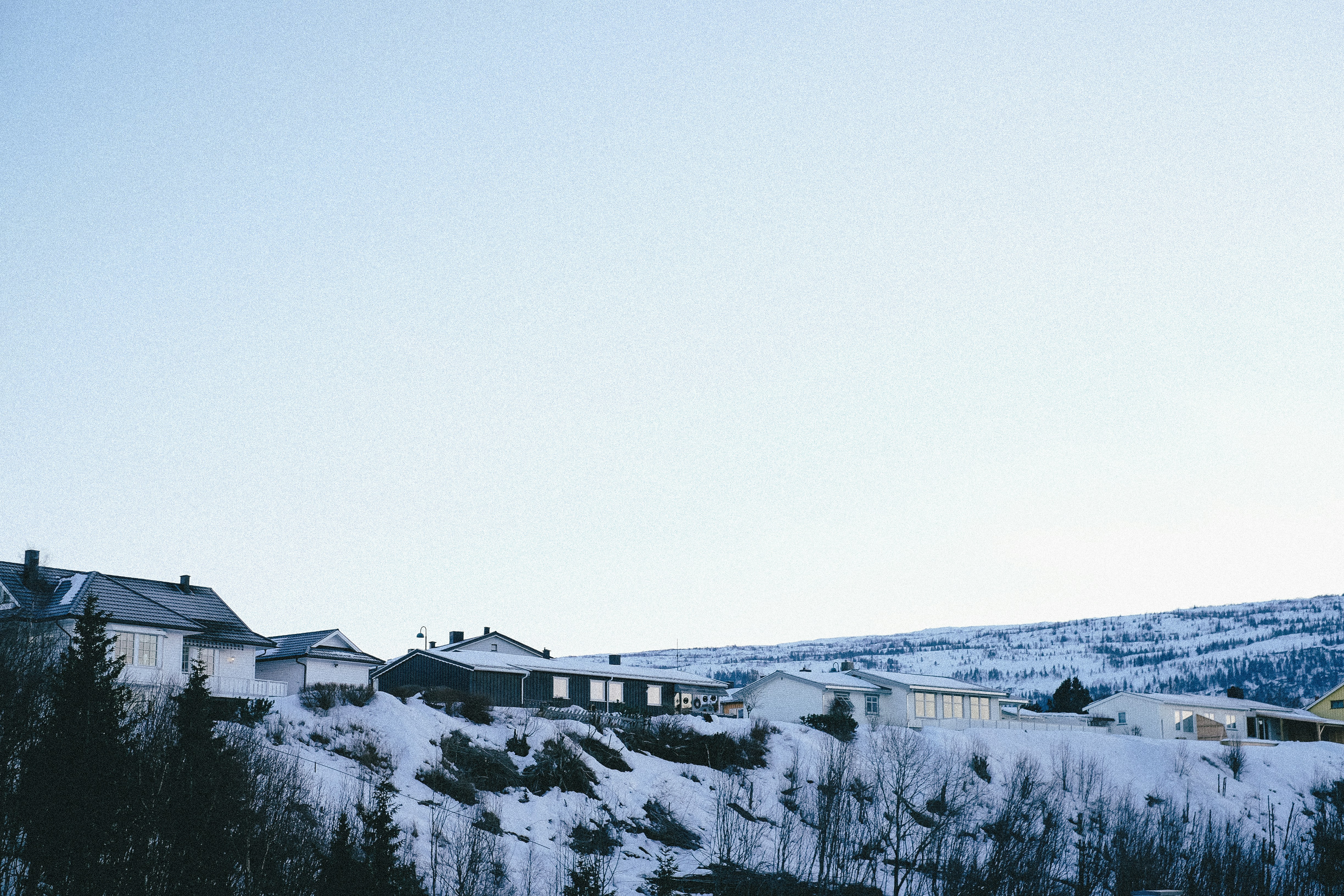 A beautiful winter wonderland scene of the homes on top of a hill covered in snow.