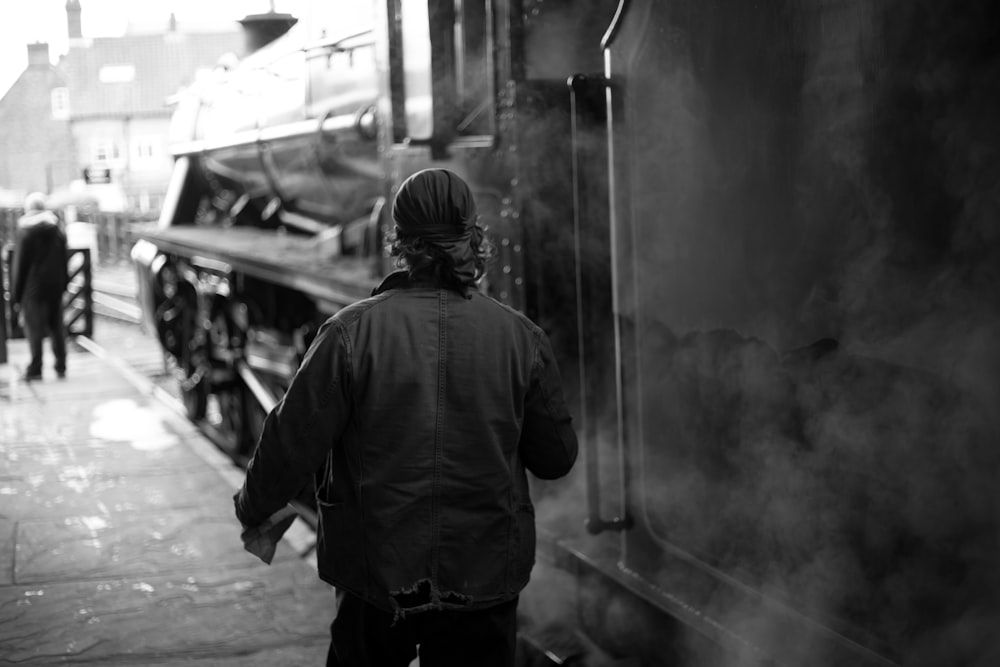 grayscale photo of man in jacket standing