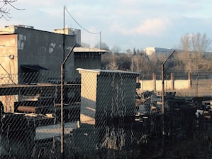 Wide shot of sturdy fencing protecting a busy industrial area with heavy machinery in the background.