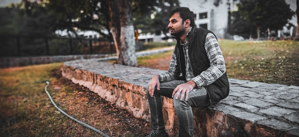 man in black and white striped long sleeve shirt and blue denim jeans sitting on brown