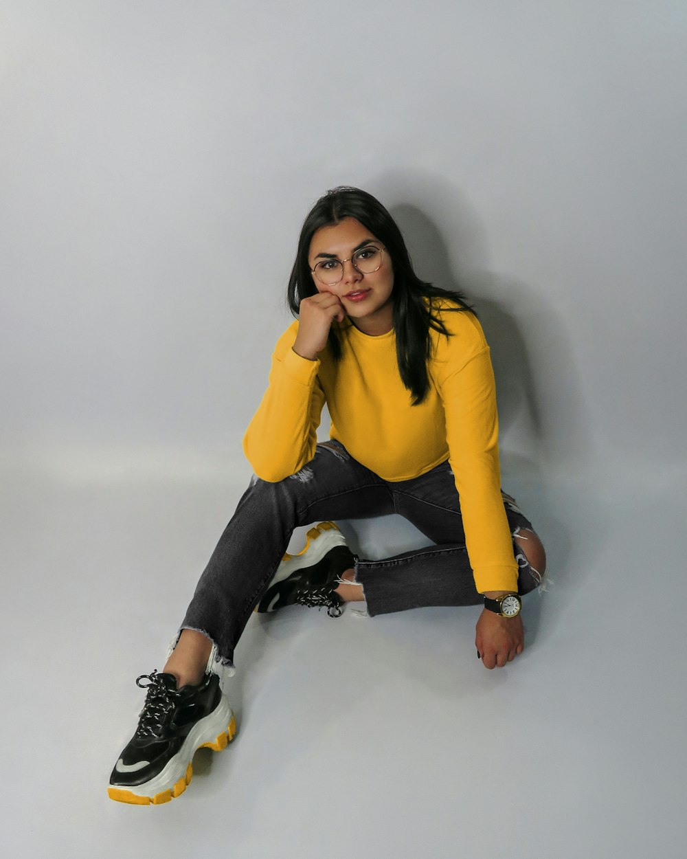 woman in yellow long sleeve shirt and black pants sitting on white table