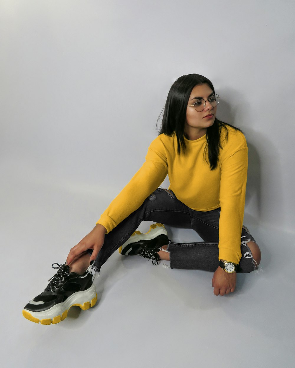 woman in yellow long sleeve shirt and black pants sitting on white floor