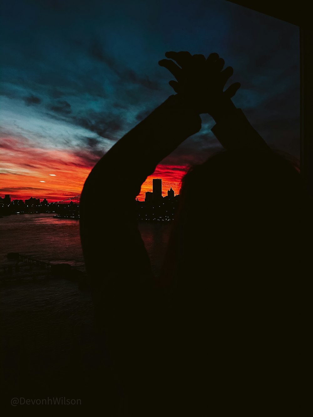 silhouette of person raising hand during sunset
