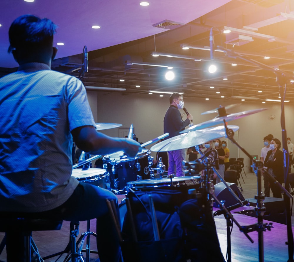 man in blue shirt playing drum