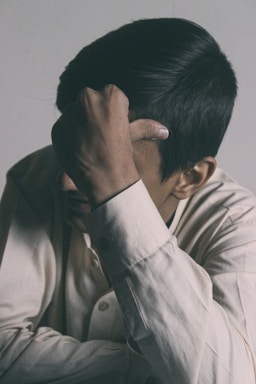 man in white button up shirt covering his face