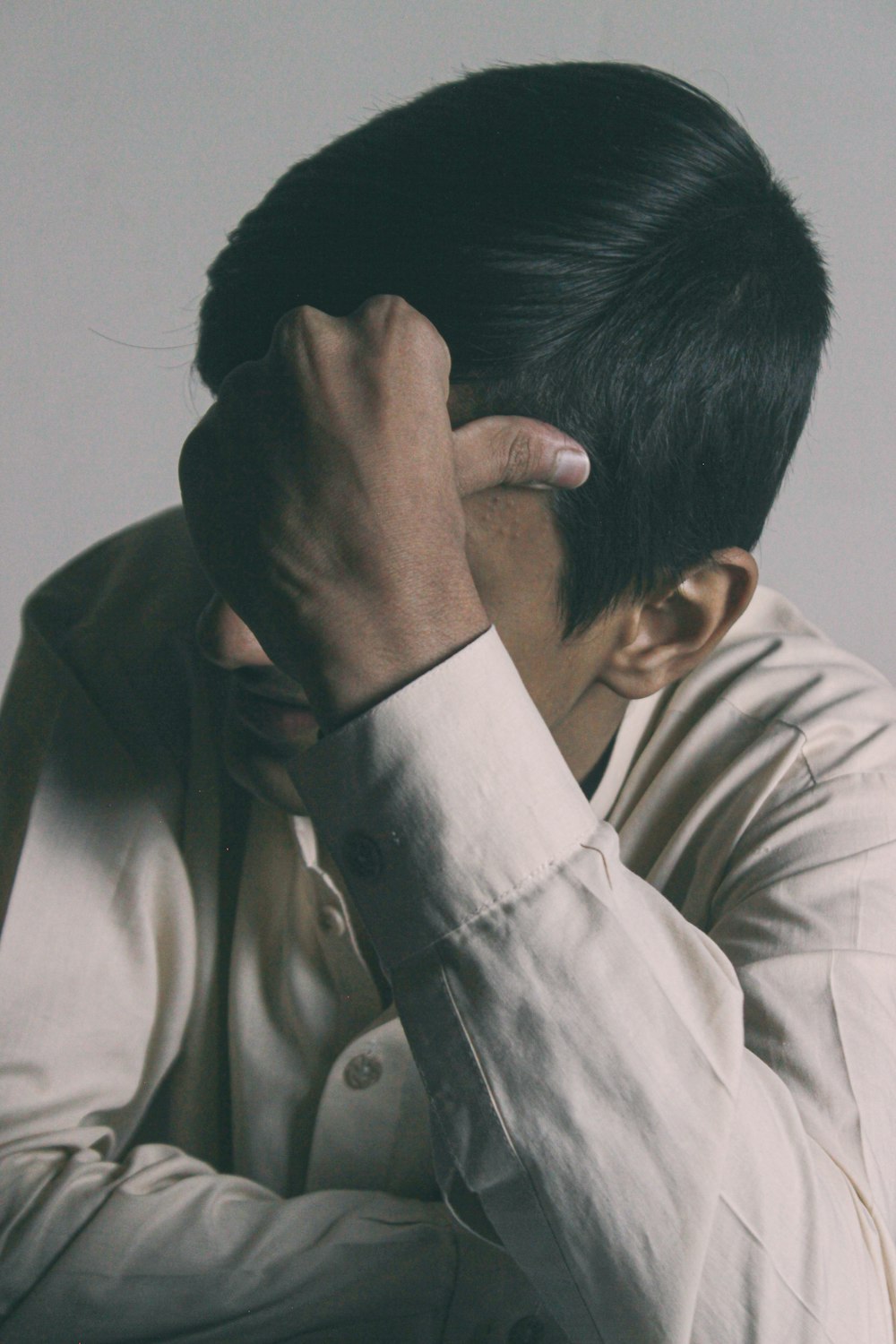 man in white button up shirt covering his face