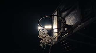 Close-up shot of a worn basketball on cracked asphalt under city streetlights.