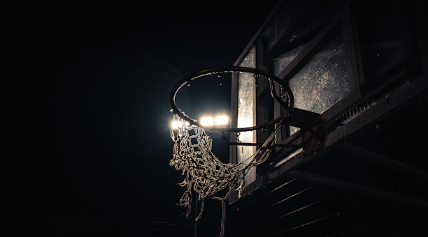 Close-up shot of a worn basketball on cracked asphalt under city streetlights.