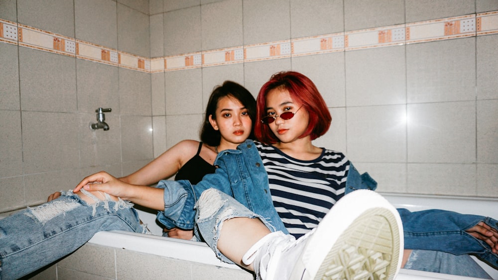 woman in blue denim shorts lying on white ceramic bathtub