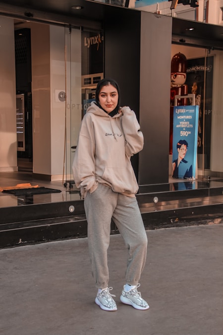 Woman in an oversized white hoodie leaning against a dark wooden table