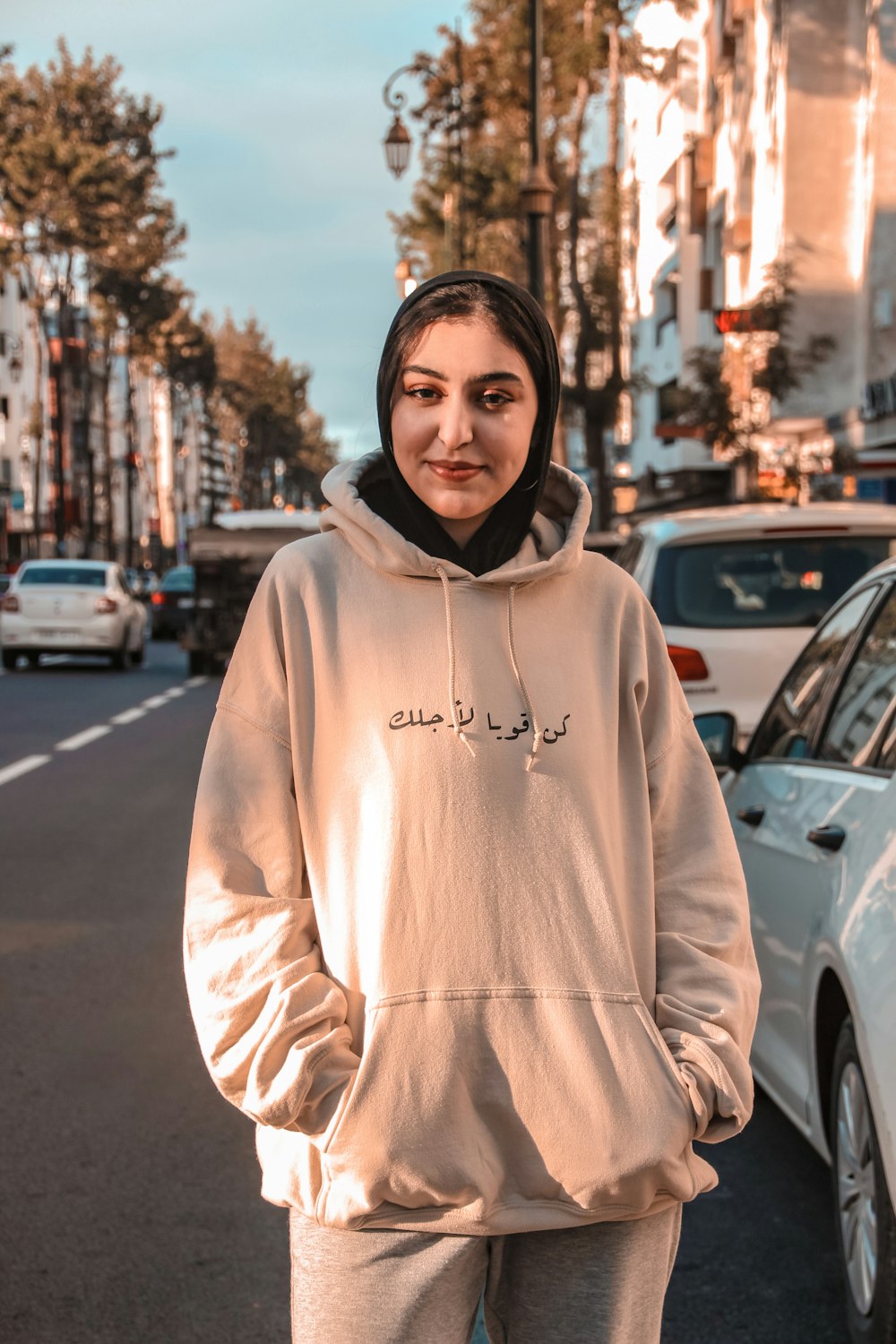 man in white pullover hoodie standing on road during daytime