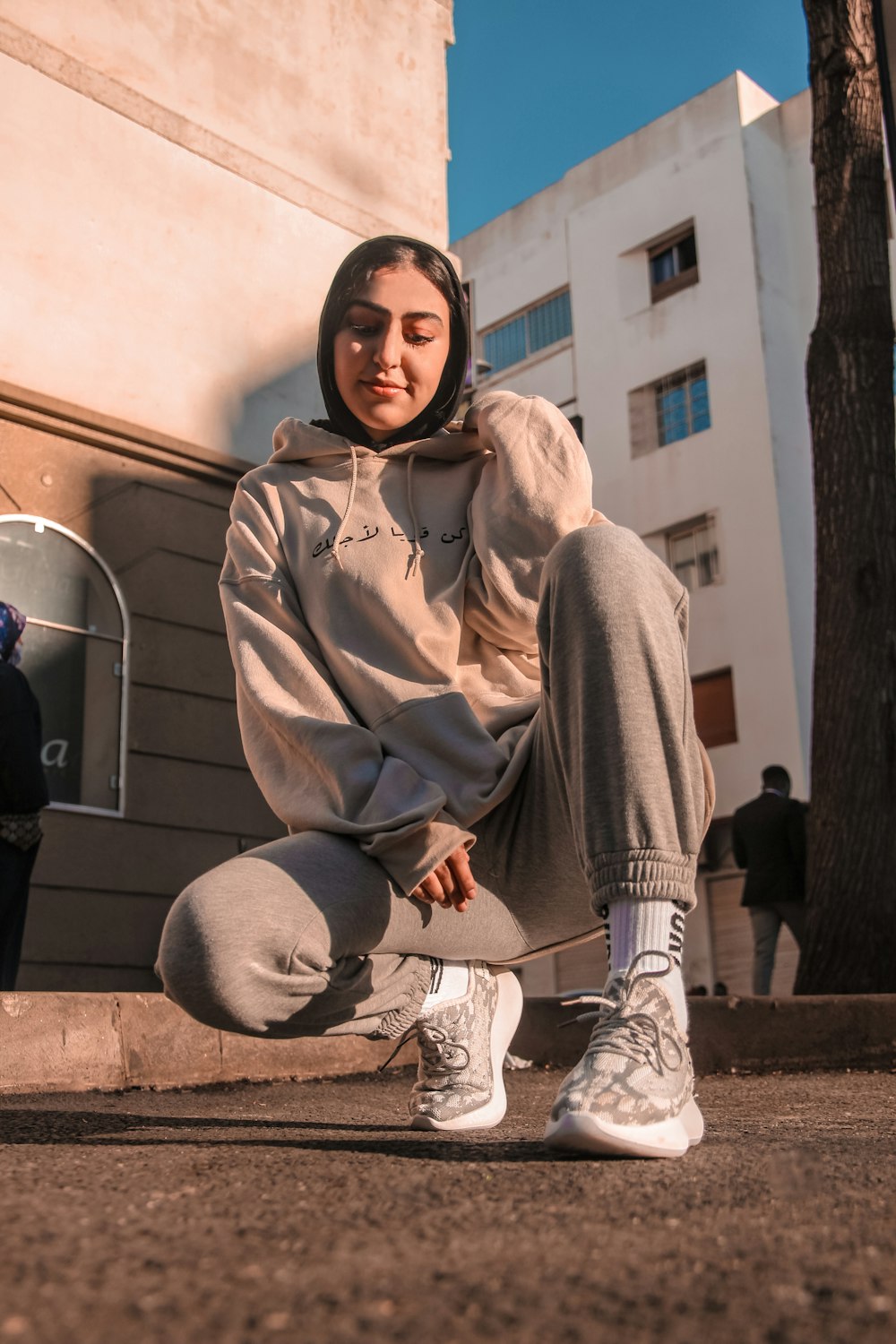 woman in gray hoodie sitting on concrete bench