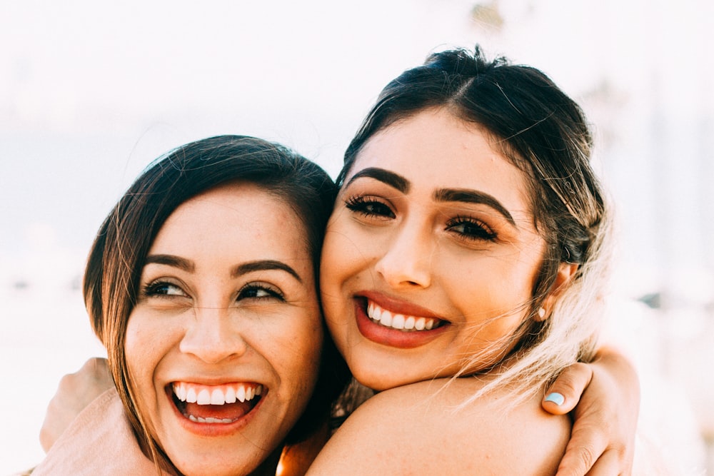 woman smiling beside topless woman